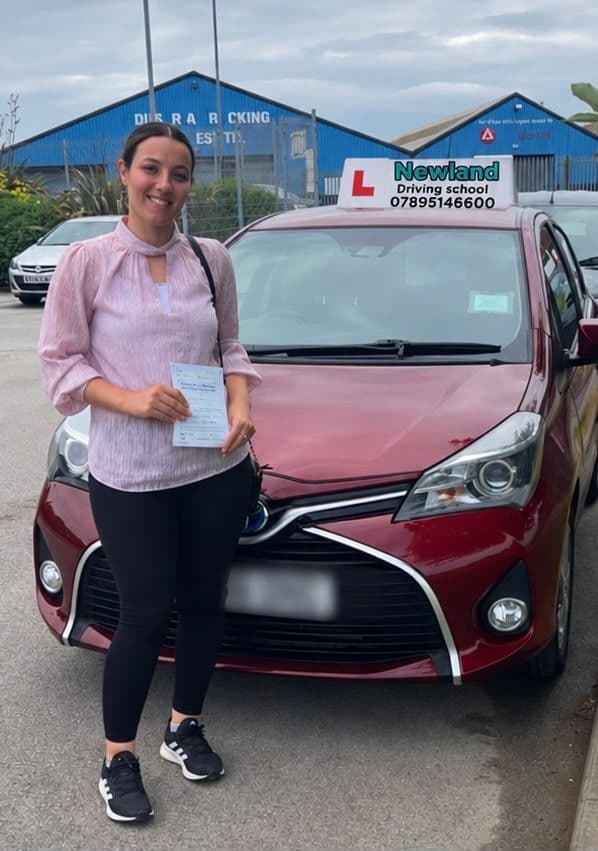 Pass photo 1: pupil with their pass certificate beside the red Toyota Yaris
