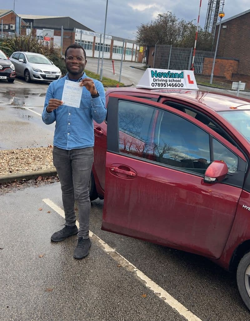 Pass photo 3: pupil with their pass certificate beside the red Toyota Yaris