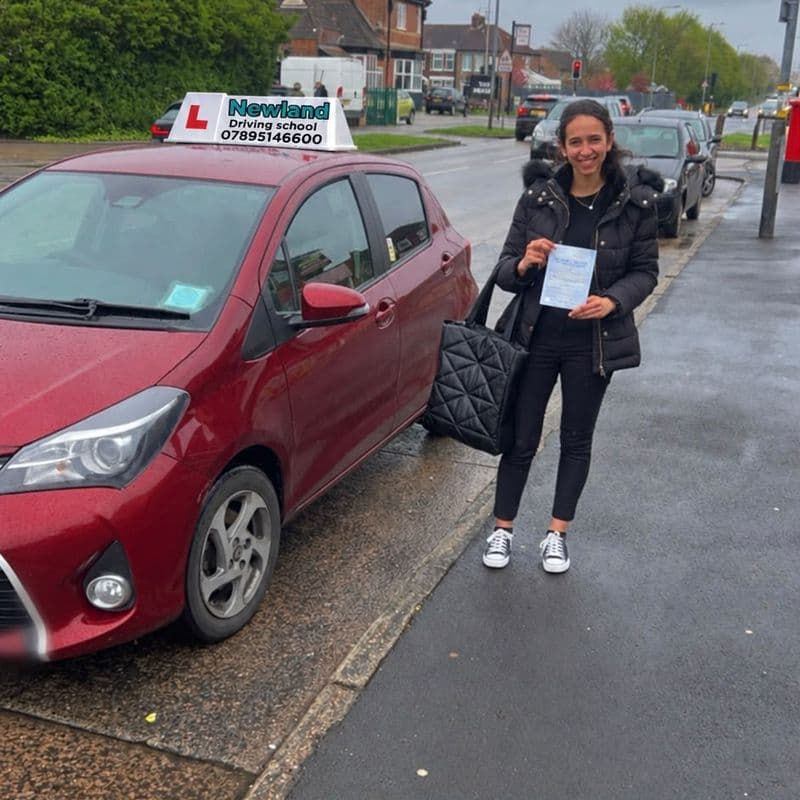 Pass photo 4: pupil with their pass certificate beside the red Toyota Yaris