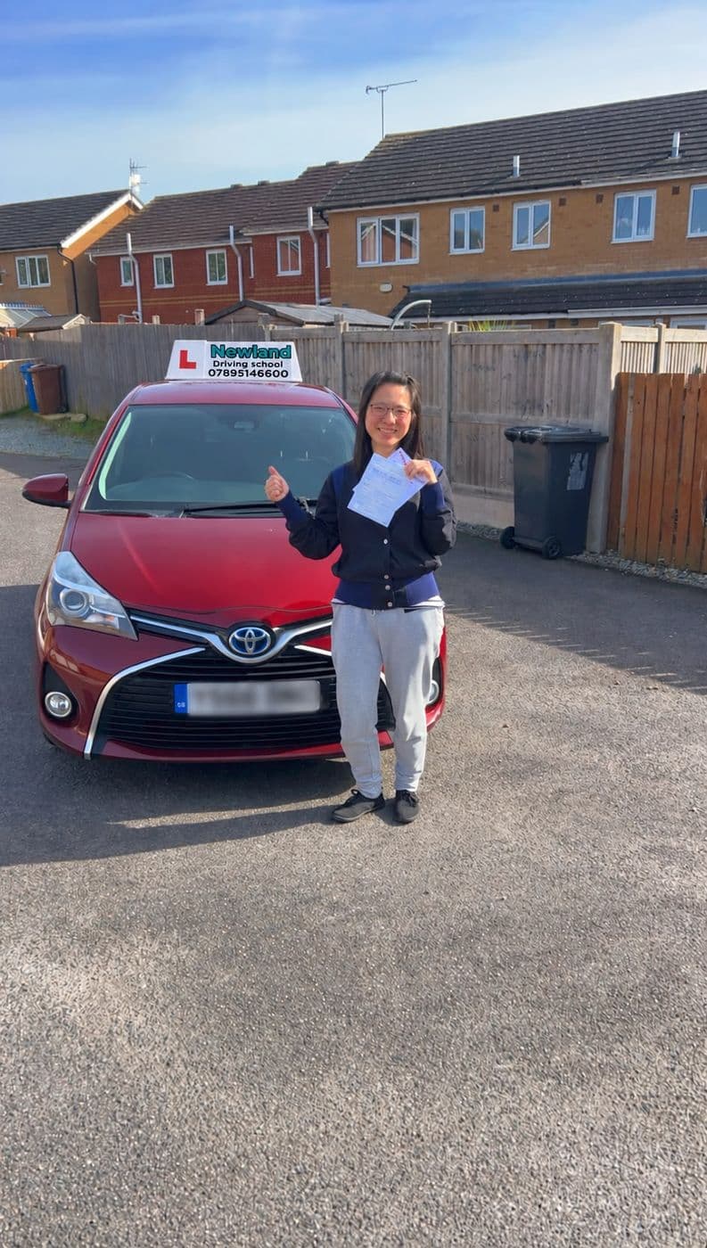 Pass photo 5: pupil with their pass certificate beside the red Toyota Yaris