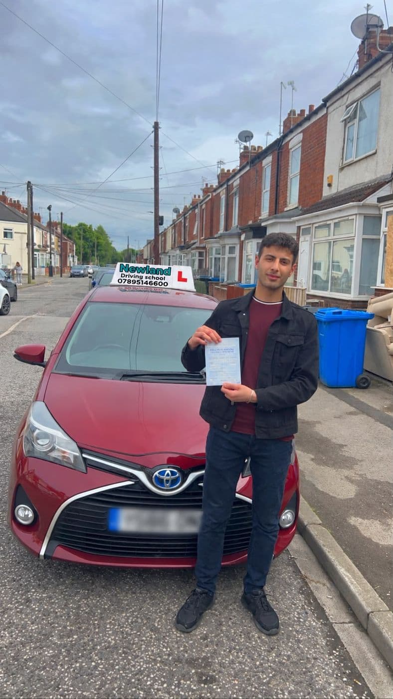 Pass photo 8: pupil with their pass certificate beside the red Toyota Yaris