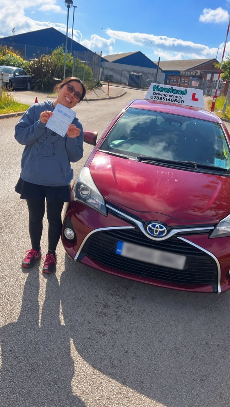 Pass photo 9: pupil with their pass certificate beside the red Toyota Yaris