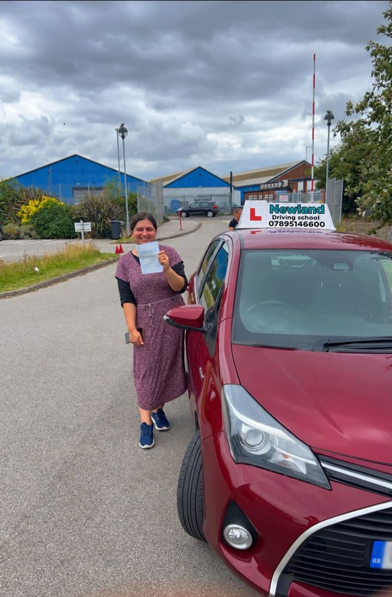 Pass photo 10: pupil with their pass certificate beside the red Toyota Yaris