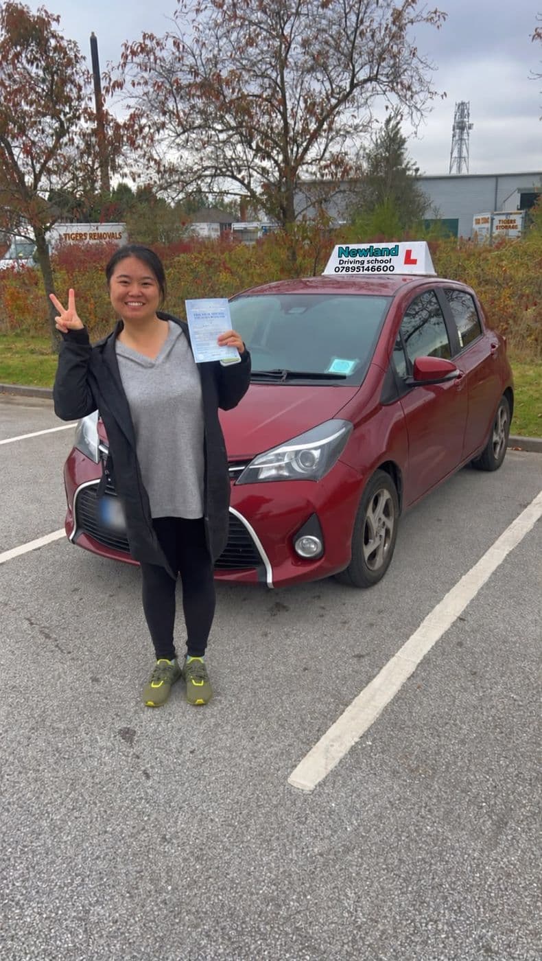 Pass photo 12: pupil with their pass certificate beside the red Toyota Yaris
