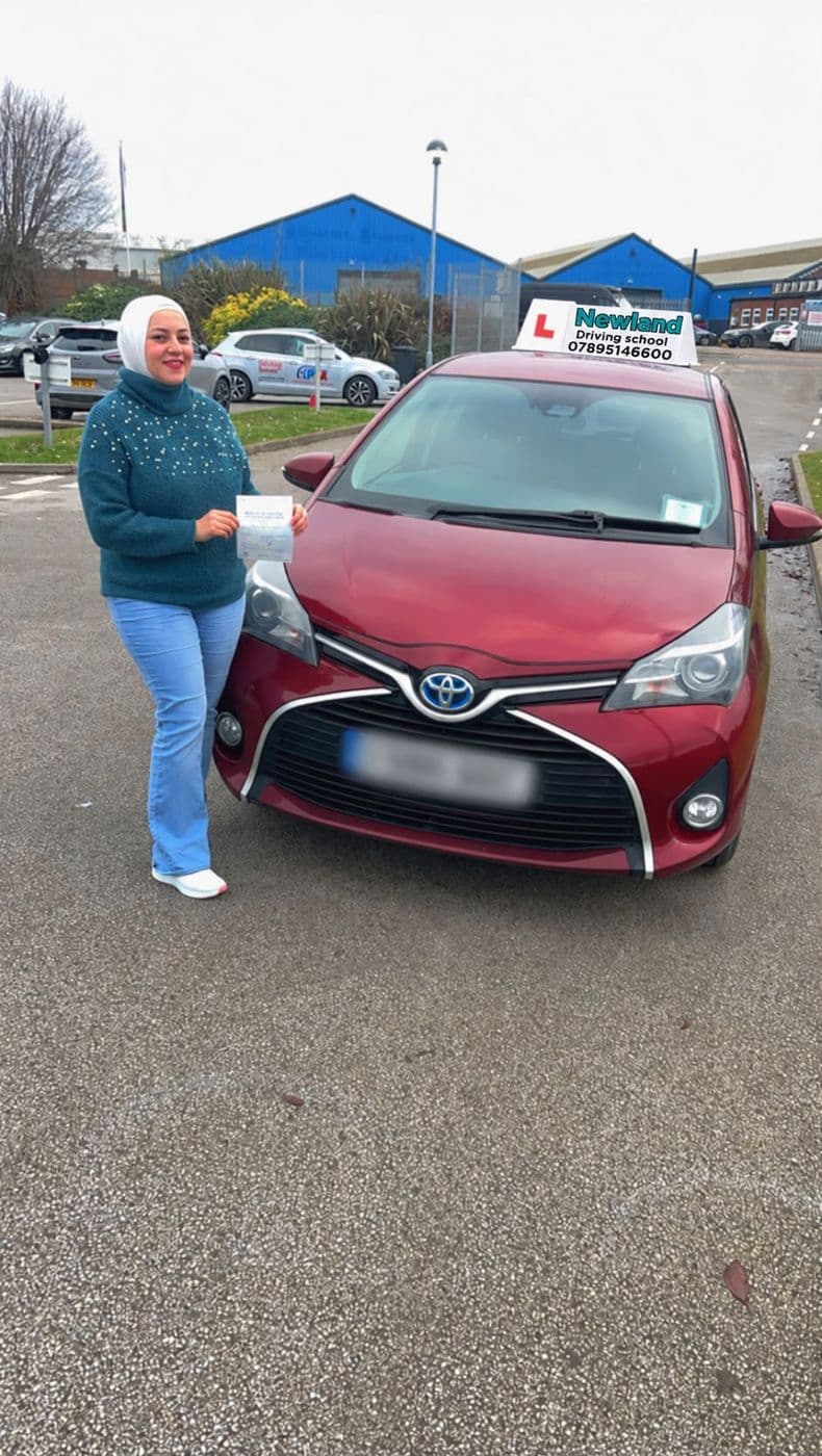Pass photo 14: pupil with their pass certificate beside the red Toyota Yaris