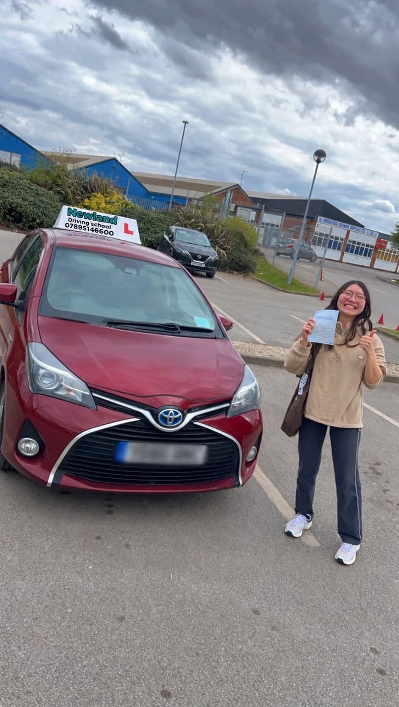 Pass photo 18: pupil with their pass certificate beside the red Toyota Yaris