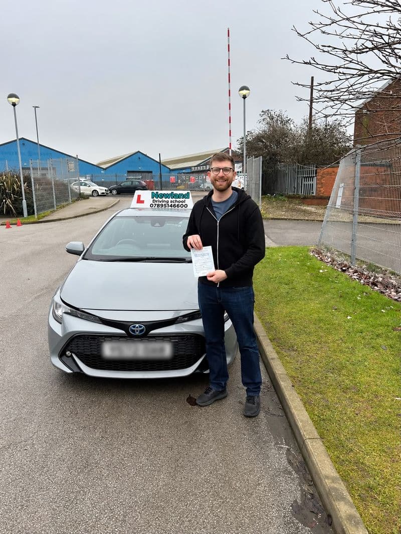 Pass photo 21: pupil with their pass certificate beside the silver Toyota