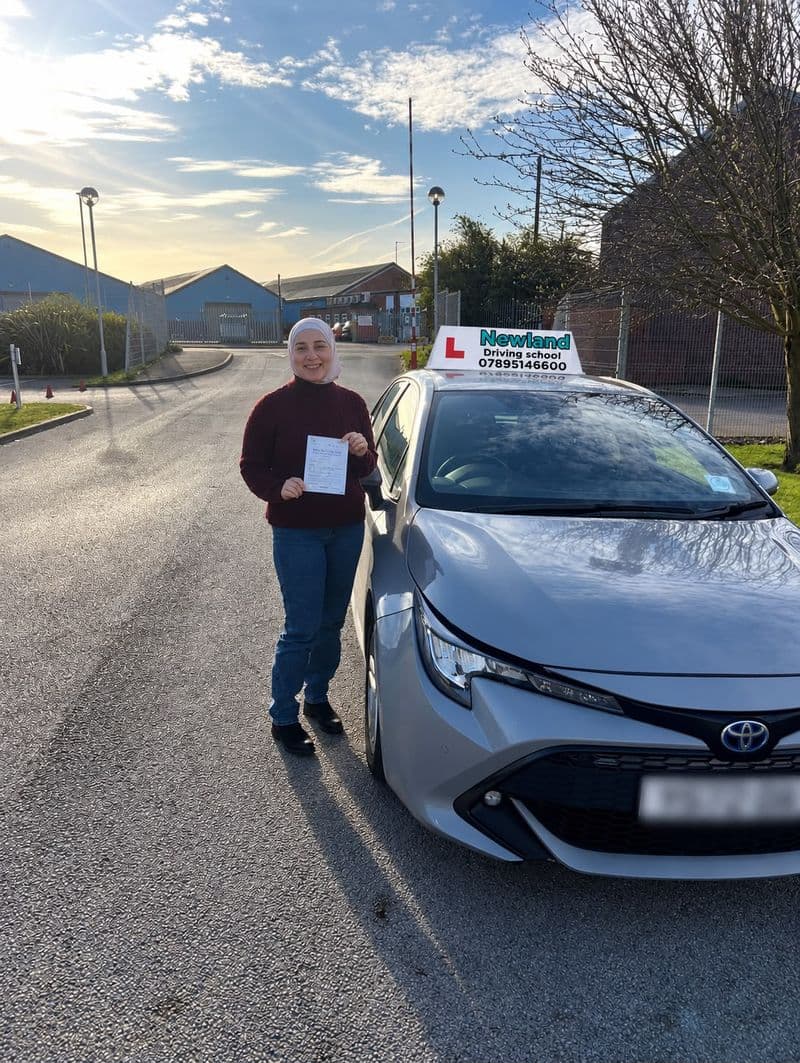 Pass photo 25: pupil with their pass certificate beside the silver Toyota