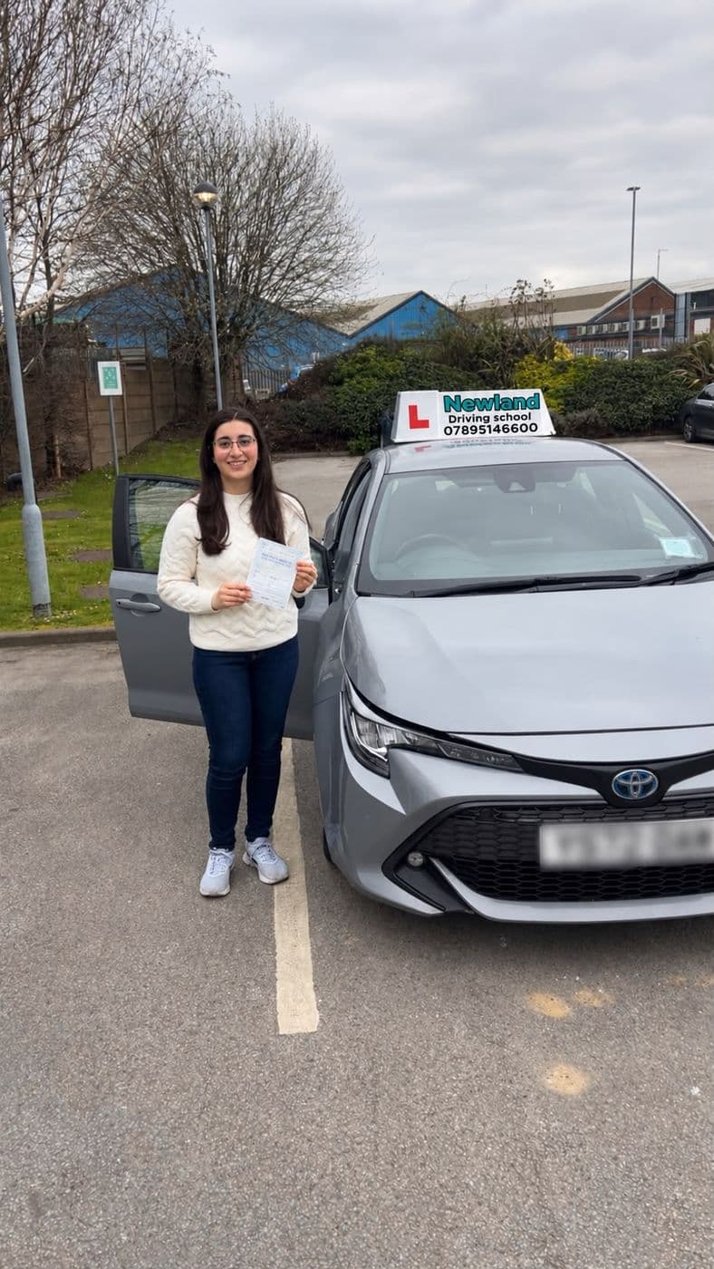 Pass photo 26: pupil with their pass certificate beside the silver Toyota