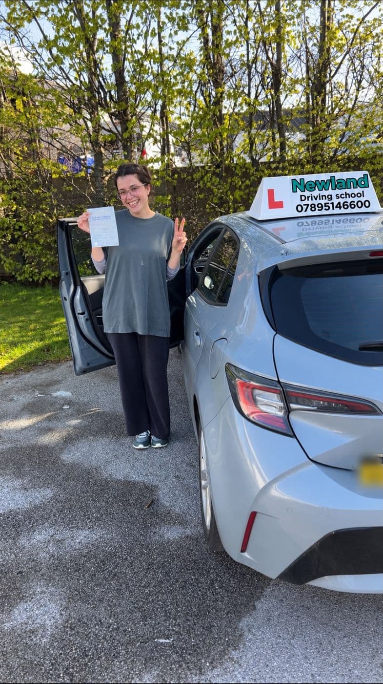 Pass photo 27: pupil with their pass certificate beside the silver Toyota