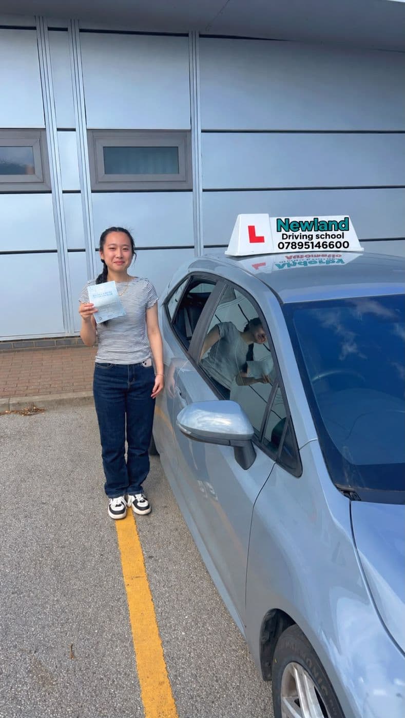 Pass photo 28: pupil with their pass certificate beside the silver Toyota