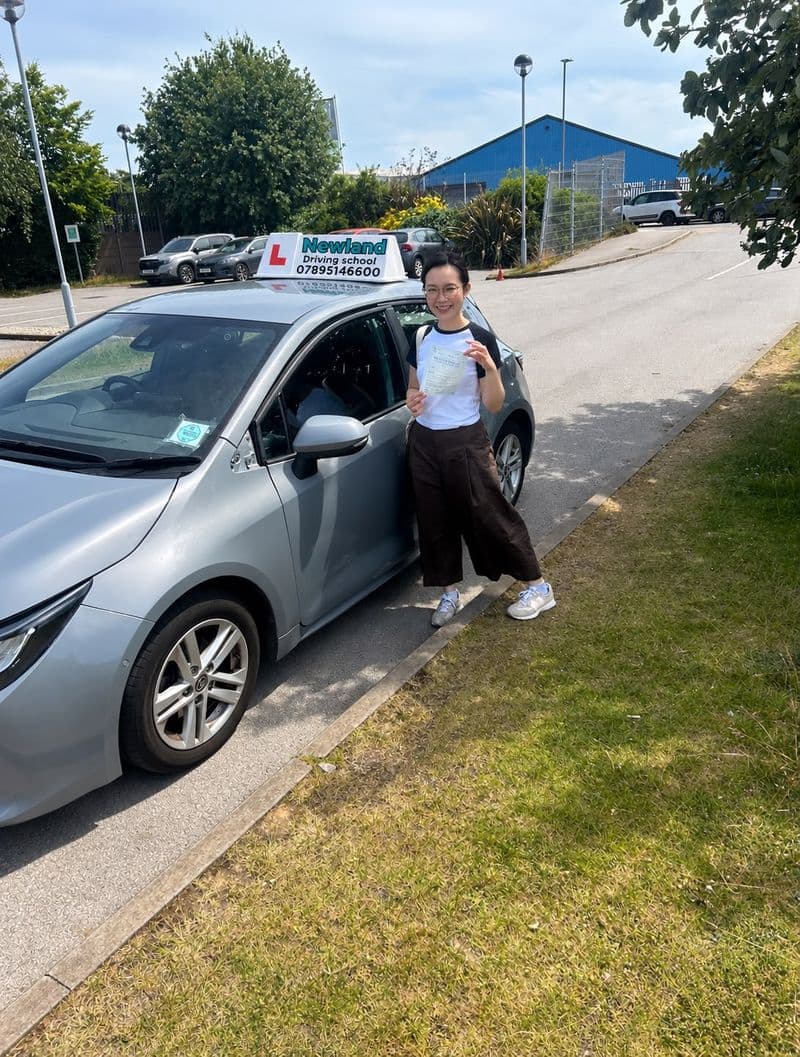 Pass photo 31: pupil with their pass certificate beside the silver Toyota