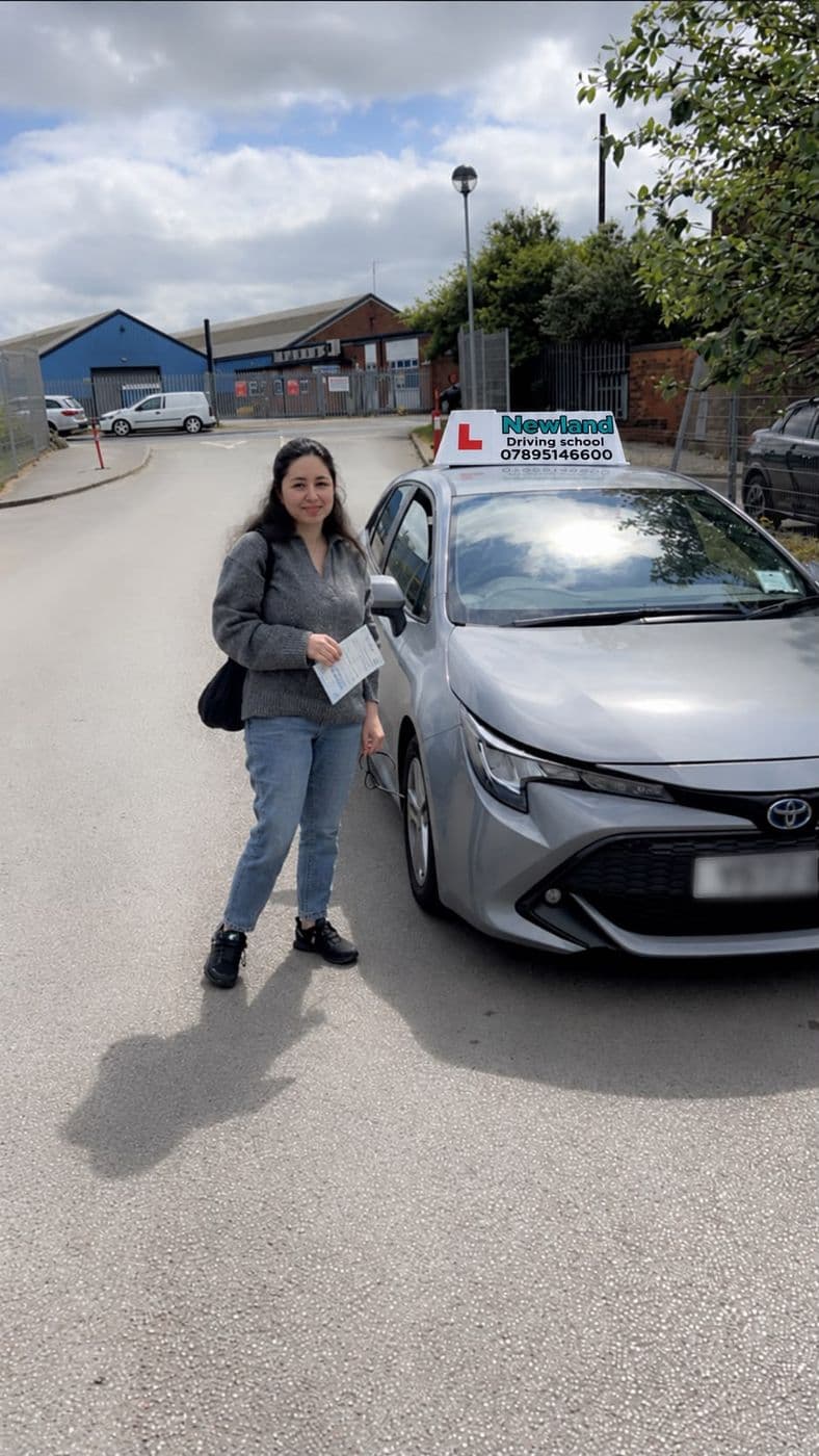 Pass photo 32: pupil with their pass certificate beside the silver Toyota