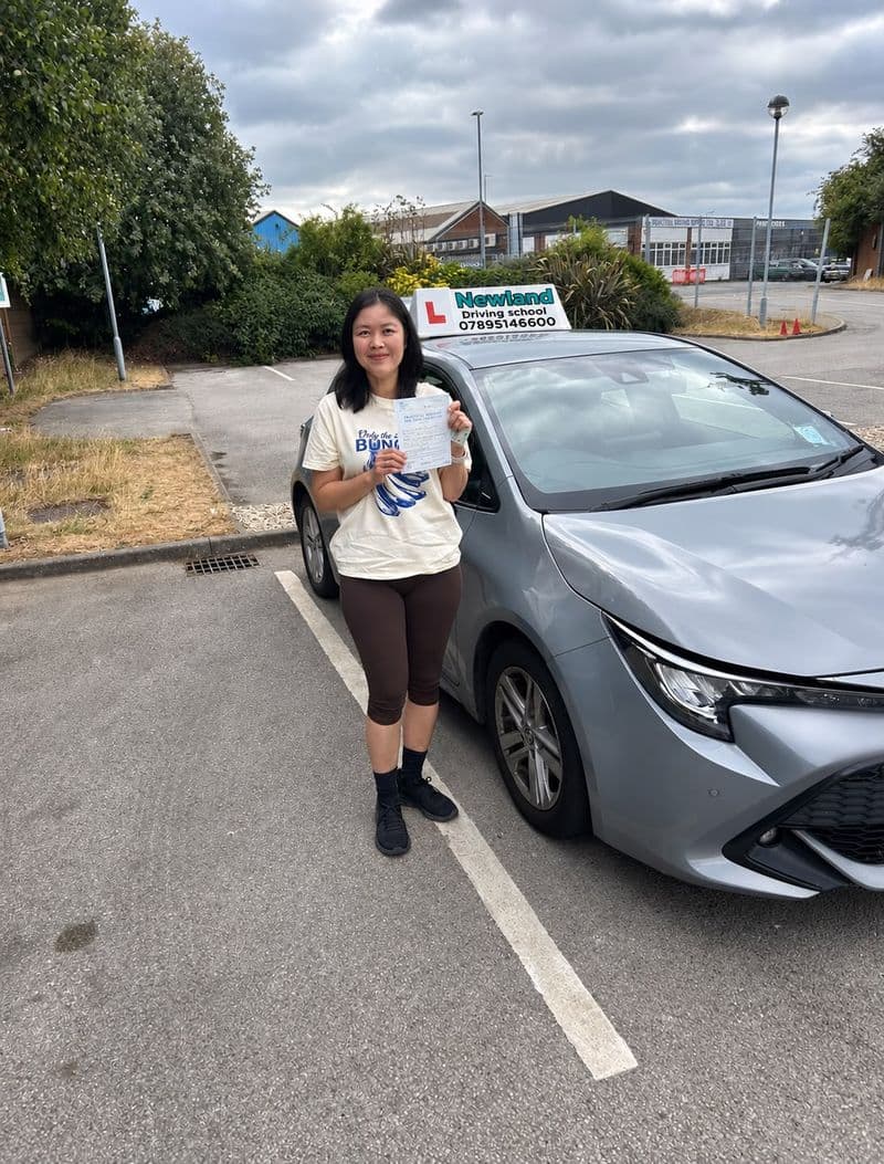 Pass photo 33: pupil with their pass certificate beside the silver Toyota