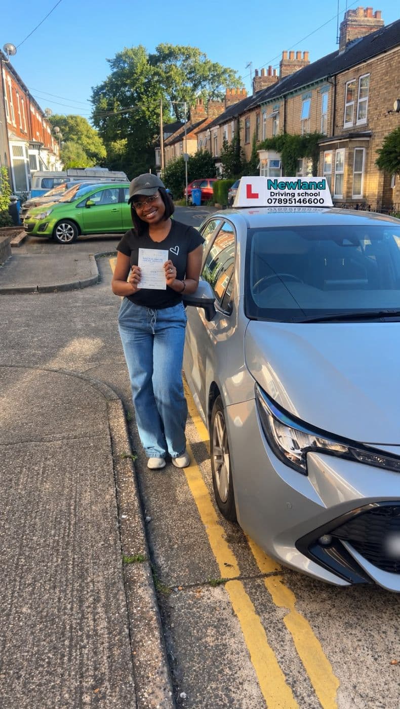 Pass photo 35: pupil with their pass certificate beside the silver Toyota