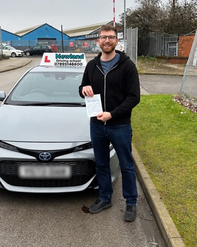 Pupil with his pass certificate beside the silver Toyota Corolla